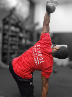 Male student at the School of Personal Training in Castle Hills, Texas, demonstrating a kettlebell exercise, highlighting practical strength training techniques learned in our personal training program.