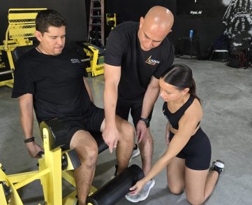 20250911_103414 Fitness instructors providing hands-on machinery guidance during a personal trainer certification practical exam.