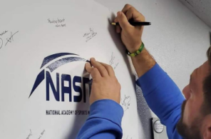 59da1-2-3 A fitness graduate signing the NASM board after successfully passing his personal trainer certification.