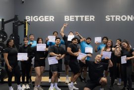 DSC01409 (1) A large class of fitness coaches celebrating their graduation from a personal trainer certification program in a gym.