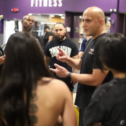 Experienced personal training instructor leading a group discussion with students at a fitness school, demonstrating active learning and mentorship for aspiring certified personal trainers.